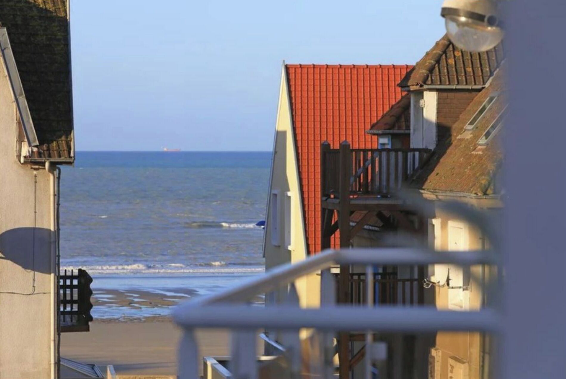 Un edificio sul lungomare con tetto rosso, un balcone e vista sul mare.