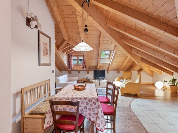 Una habitación acogedora en el ático con una mesa de comedor, sillas, un sofá y una televisión.