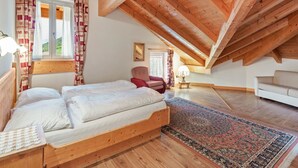 Un dormitorio con techo de madera, una cama, una silla, un sofá y una alfombra.