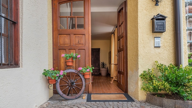 Una entrada empedrada con una puerta de madera, un buzón y macetas con plantas.