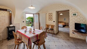 A cozy dining area with a table set for two, a fireplace, and a television in a room with an arched ceiling and patterned wallpaper.