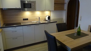 Cozinha moderna com micro-ondas, pia e área de refeições com mesa e cadeiras.