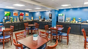 Un restaurante con paredes azules, mesas y sillas de madera, una barra con exhibiciones de comida y una máquina de café.