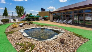 Una piscina rodeada por un patio con sillas reclinables y una bandera estadounidense.