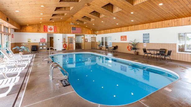 Una piscina con techo y paredes de madera, un flotador salvavidas y un cartel que dice 'No pasar la cuerda de la piscina'.