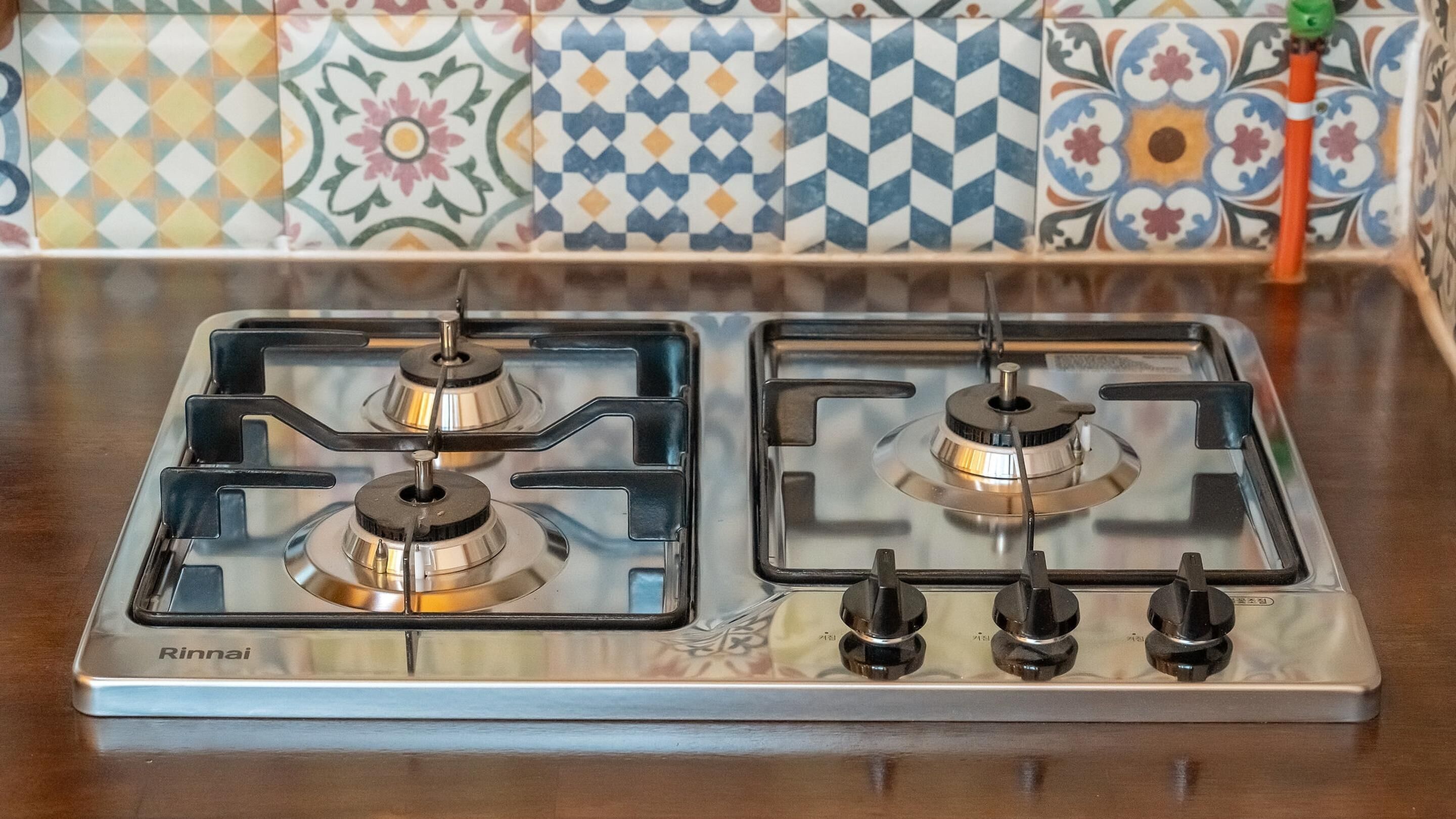 A stainless steel Rinnai gas stove with four burners and a control panel.