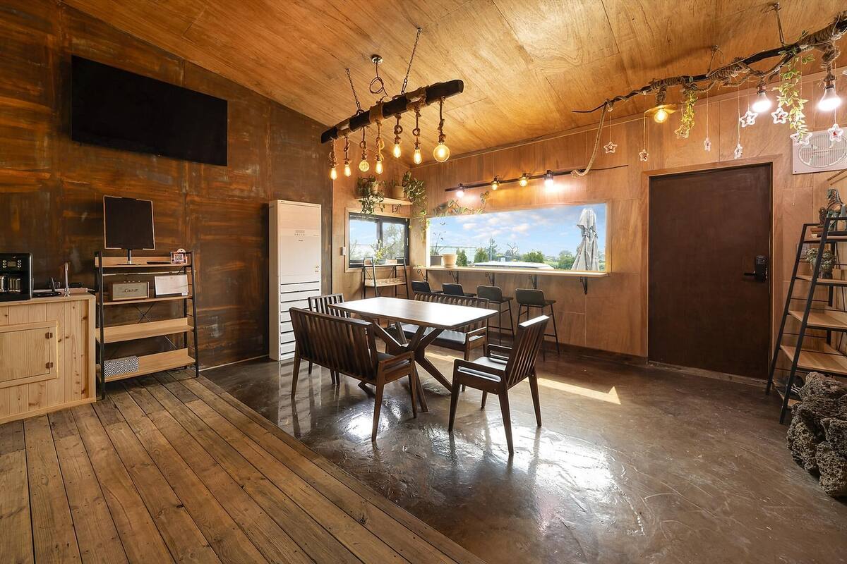 Ein Holzinterieur mit Esstisch, Stühlen, einem Fernseher und einer Küchenzeile.