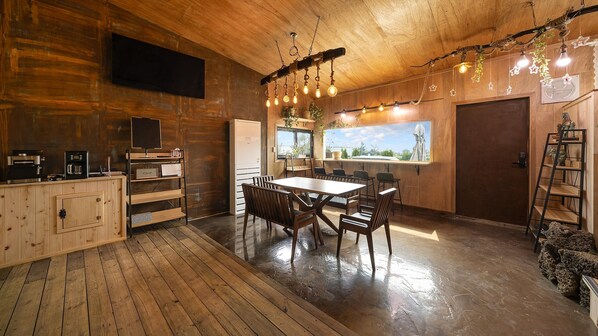 A wooden interior with a dining table, chairs, a TV, and a kitchen area. - Seogwipo Unyeong Pension (Seogwipo)