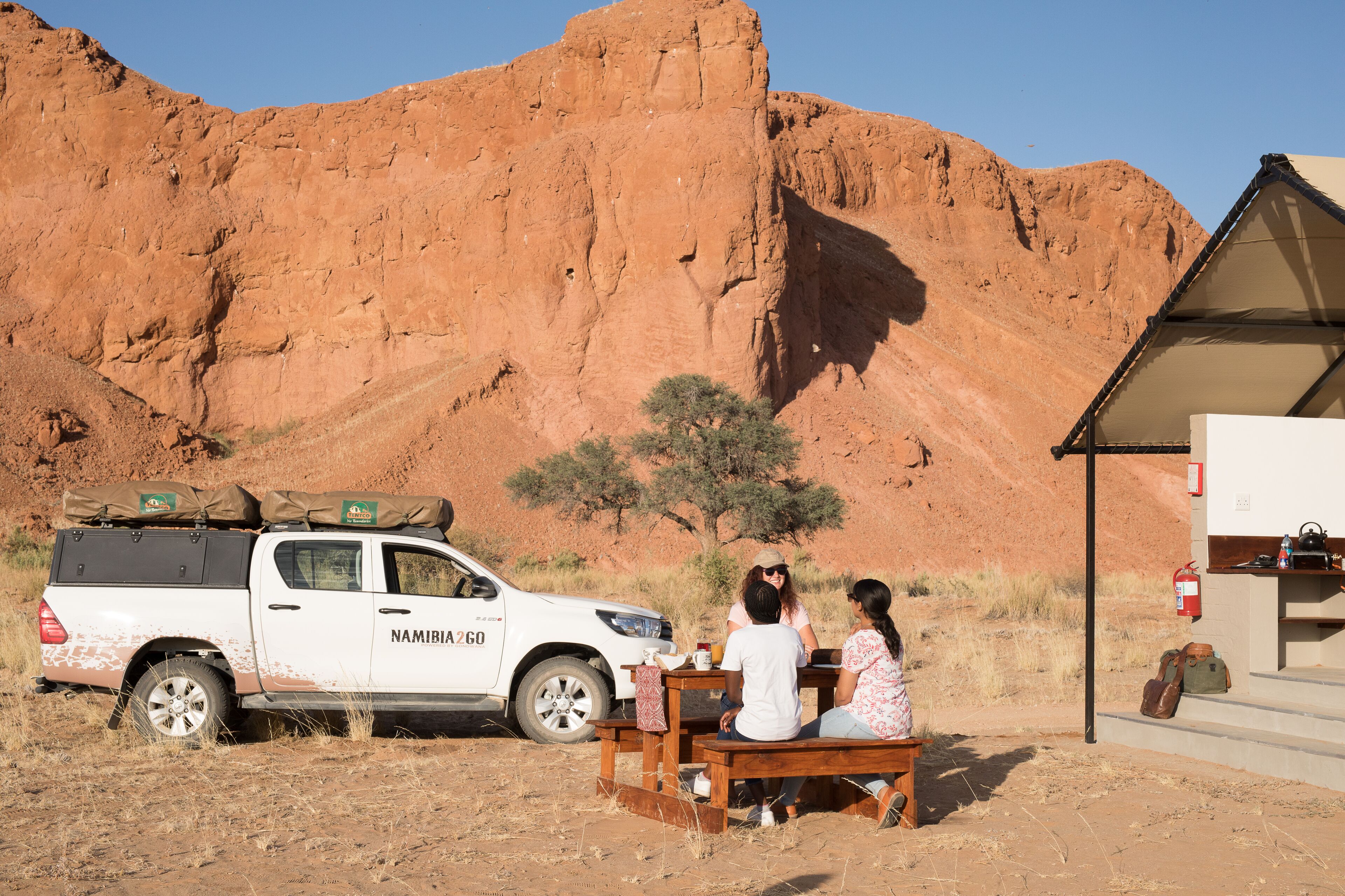 Una camioneta pickup blanca con equipaje estacionada en un paisaje desértico.