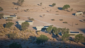 A remote, desert-style hotel with multiple buildings, each featuring solar panels on the roofs.