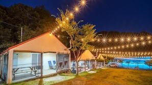 A campsite with tents, picnic tables, and string lights. - Pocheon Kidsglampinggeo (Pocheon)