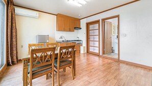 A compact kitchen with wooden cabinets, a refrigerator, and a stove. - Ganghwa Dondaemoru Pension (Incheon)