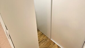 Kapea käytävä, jonka seinät ovat valkoiset ja lattia puuta.