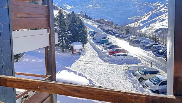 Vista nevada de una montaña con un estacionamiento y edificios en primer plano.