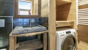 A wooden cabin bathroom with a stone sink, a mirror, and a washing machine.