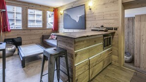 A cozy cabin interior with a wooden interior, a dining area with a bench and table, and a kitchen area with a bar counter.