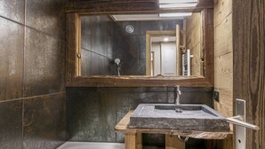 A bathroom with a wooden vanity, a large mirror, and a bathtub.