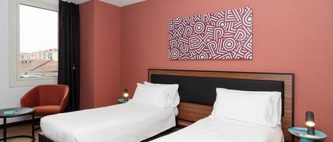 Una habitación de hotel con dos camas, una silla, una mesita y una obra de arte en la pared.