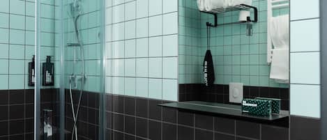 A bathroom with a glass-enclosed shower, a white sink, and a mirror above it.