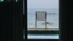 Vista del mar a través de una ventana, con un letrero en primer plano.