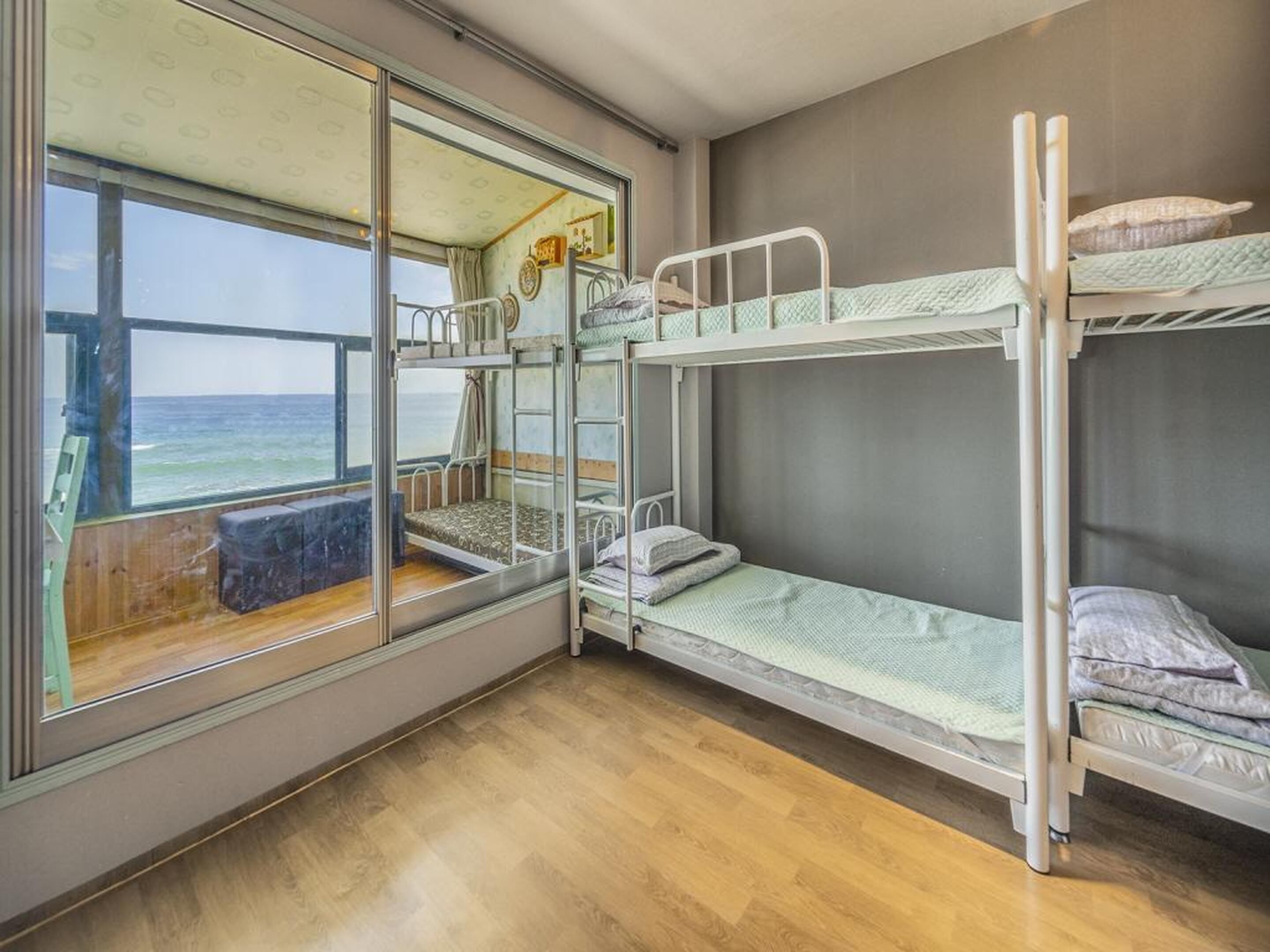 Een slaapkamer met stapelbedden, een raam met uitzicht op zee, en een houten vloer.