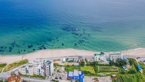 Vista aérea de un pueblo costero con edificios, una playa y aguas azules cristalinas.