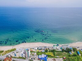 Vista aérea de un pueblo costero con edificios, una playa y aguas azules cristalinas.