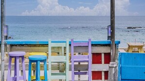 Vista al mar con valla de madera y taburetes coloridos.