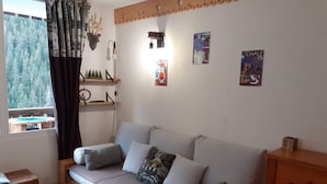 Um quarto aconchegante com sofá-cama, uma mesinha de madeira e uma janela com cortinas.