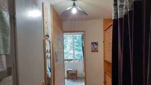 Um corredor com uma porta de madeira, uma pequena mesa e um cartaz na parede.