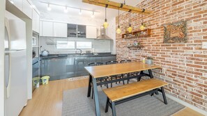 Una cocina moderna con pared de ladrillo, mesa de comedor de madera y sillas negras.