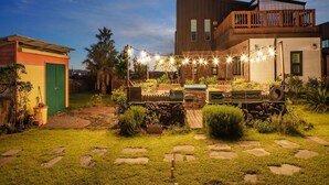 A modern house with a backyard featuring a stone pathway, a small garden, and string lights. - Jeju Jongdalrifeel House (Jeju City)