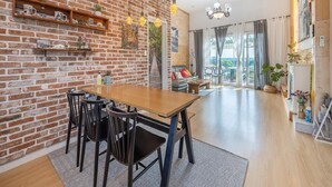 A dining area with a brick wall, wooden table, and chairs. There are shelves with plants and decorative items. - Jeju Jongdalrifeel House (Jeju City)