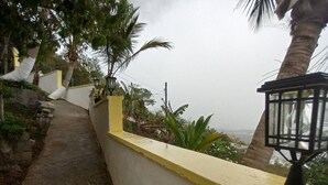Un sendero junto a un muro amarillo y un farol, que conduce a vistas del océano.