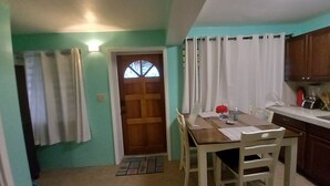 Cocina compacta con comedor, puerta de madera con ventana y una lámpara sobre la puerta.
