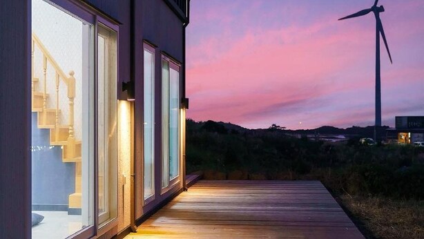 A modern house with large windows and a wooden deck.