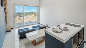 A modern room with a large sliding glass door leading to a balcony, a small seating area with cushions, and a table with tea set.