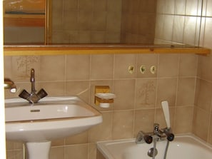 Ein Badezimmer mit Waschbecken, Spiegel, Badewanne und Handtuchhalter.