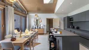 A modern kitchen with a central island, dark cabinetry, and a skylight above the dining area. - Duplex in Megève with spa, pool, gym and fireplace (Megève)