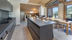 A modern kitchen with a large island, a dining area with a view, and a cozy seating space. - Duplex in Megève with spa, pool, gym and fireplace (Megève)