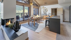 A spacious living area with a fireplace, dining table, and a view of the outdoors. - Duplex in Megève with spa, pool, gym and fireplace (Megève)