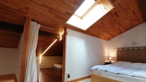 A bedroom with a wooden ceiling, a skylight, a bed, and a nightstand. - Renovated mezzanine studio for 4, near gondola in Pra Loup (Pra-Loup)