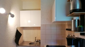 A kitchen with white cabinets, a stainless steel sink, a coffee maker, and a kettle on the countertop. - Renovated mezzanine studio for 4, near gondola in Pra Loup (Pra-Loup)