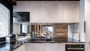 A modern kitchen with a built-in oven, a stainless steel range, and a large island with a sink. - Charming 3-BR Apartment in Megève, Near Center, Ski, and Sports Complex (Megève)