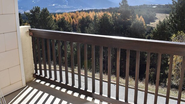 A balcony with a view of snow-capped mountains and autumn-colored trees.