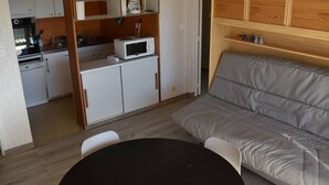 A compact living space with a kitchenette, a sofa, and a dining table.