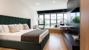 Et moderne hotelværelse med en stor seng, et skrivebord og udsigt over byen.