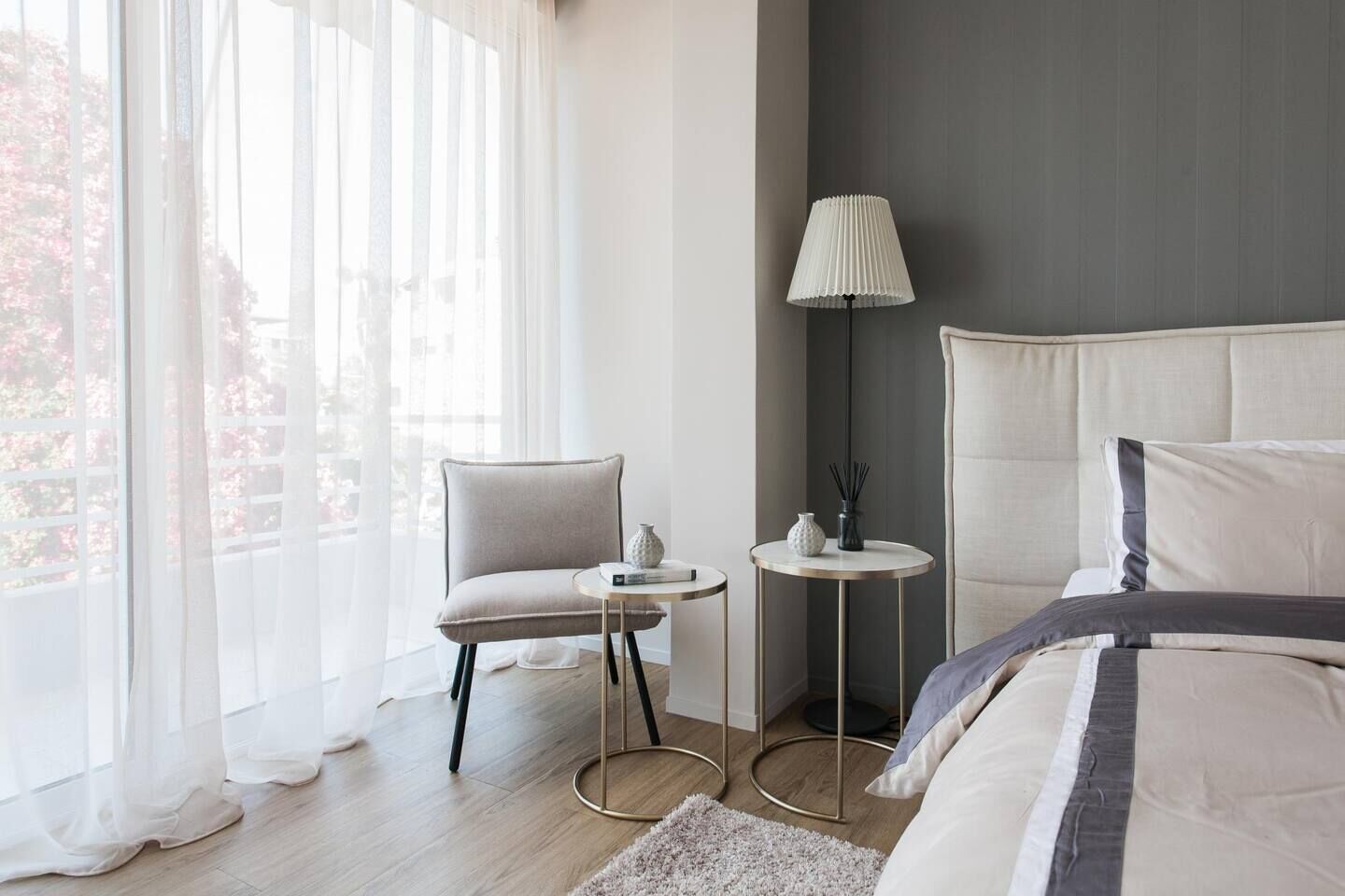 A modern bedroom with a large bed, a chair, a small table, and a lamp.