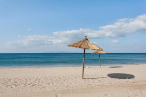 A beach with two thatched umbrellas and a clear view of the ocean. - 2BD Beachfront Apartment Athens Riviera by TheOlon (Glyfada)