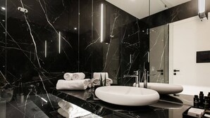 Um banheiro moderno com um espelho grande, duas pias e piso de mármore.